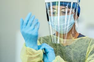 Woman dons PPE in a clinical setting