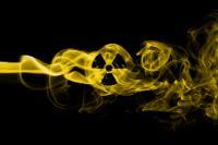 The radiology symbol appears in a wisp of yellow smoke being blown from left to right across a black background.