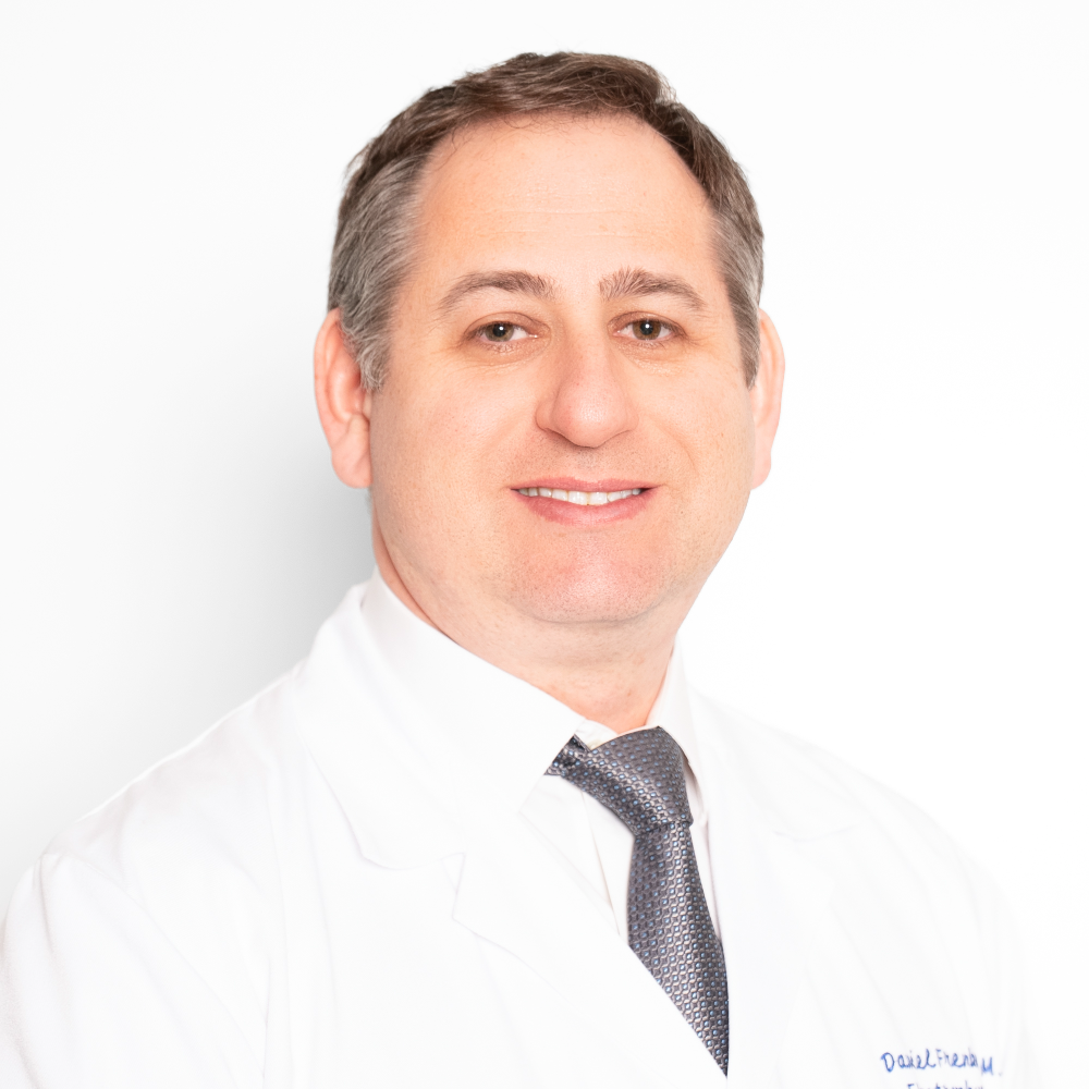 man with short dark hair wearing white coat and tie in front of white background