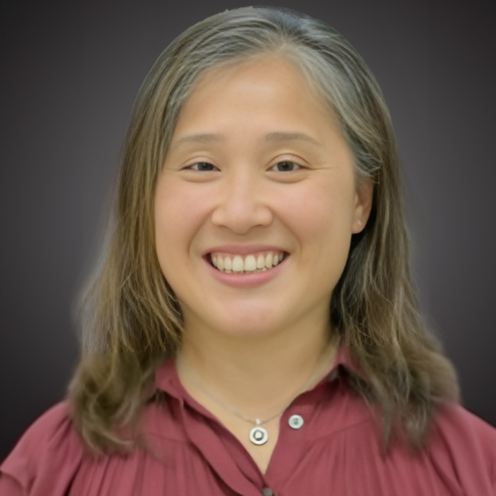 asian woman with gray hair wearing maroon top in front of gray background