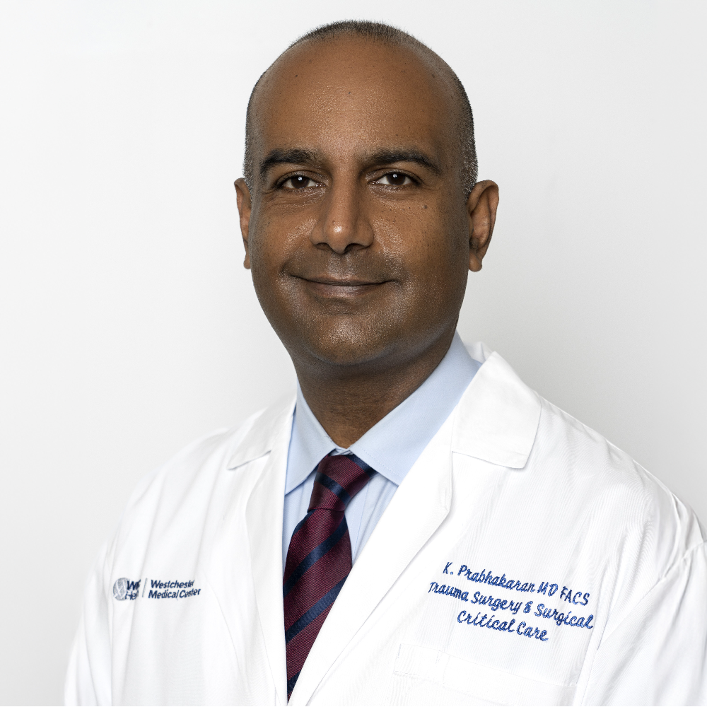 Dark-skinned man wearing white coat and blue shirt and maroon striped tie