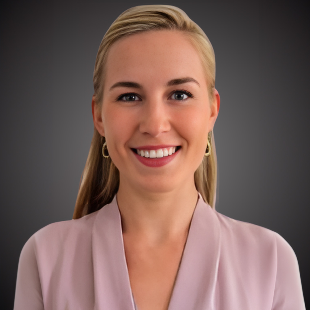 blond woman wearing pink top in front of dark gray background