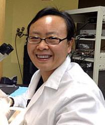 Portrait of Dr Lin smiling, wearing white lab coat in laboratory.