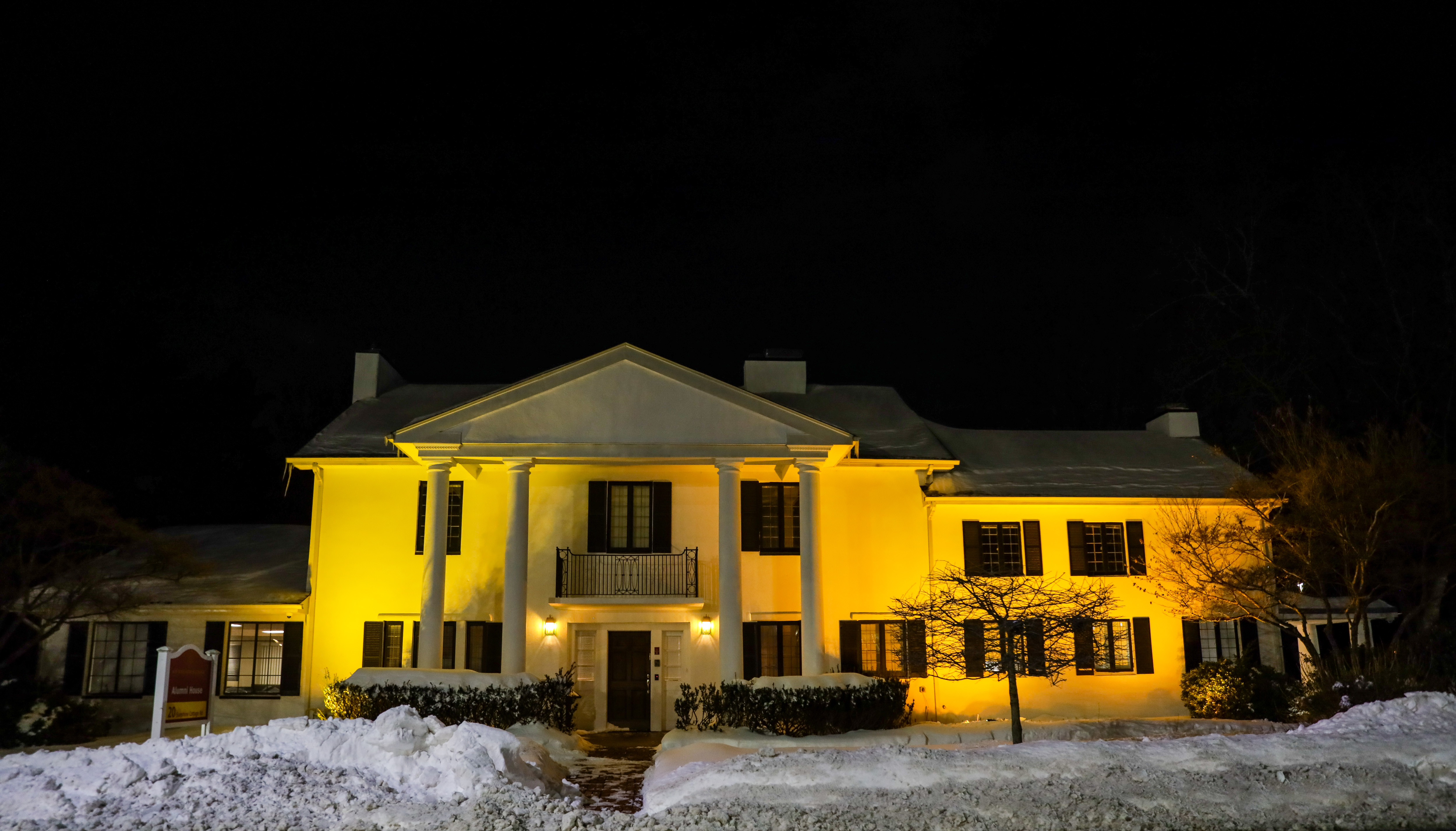A white house with snow around lit yellow