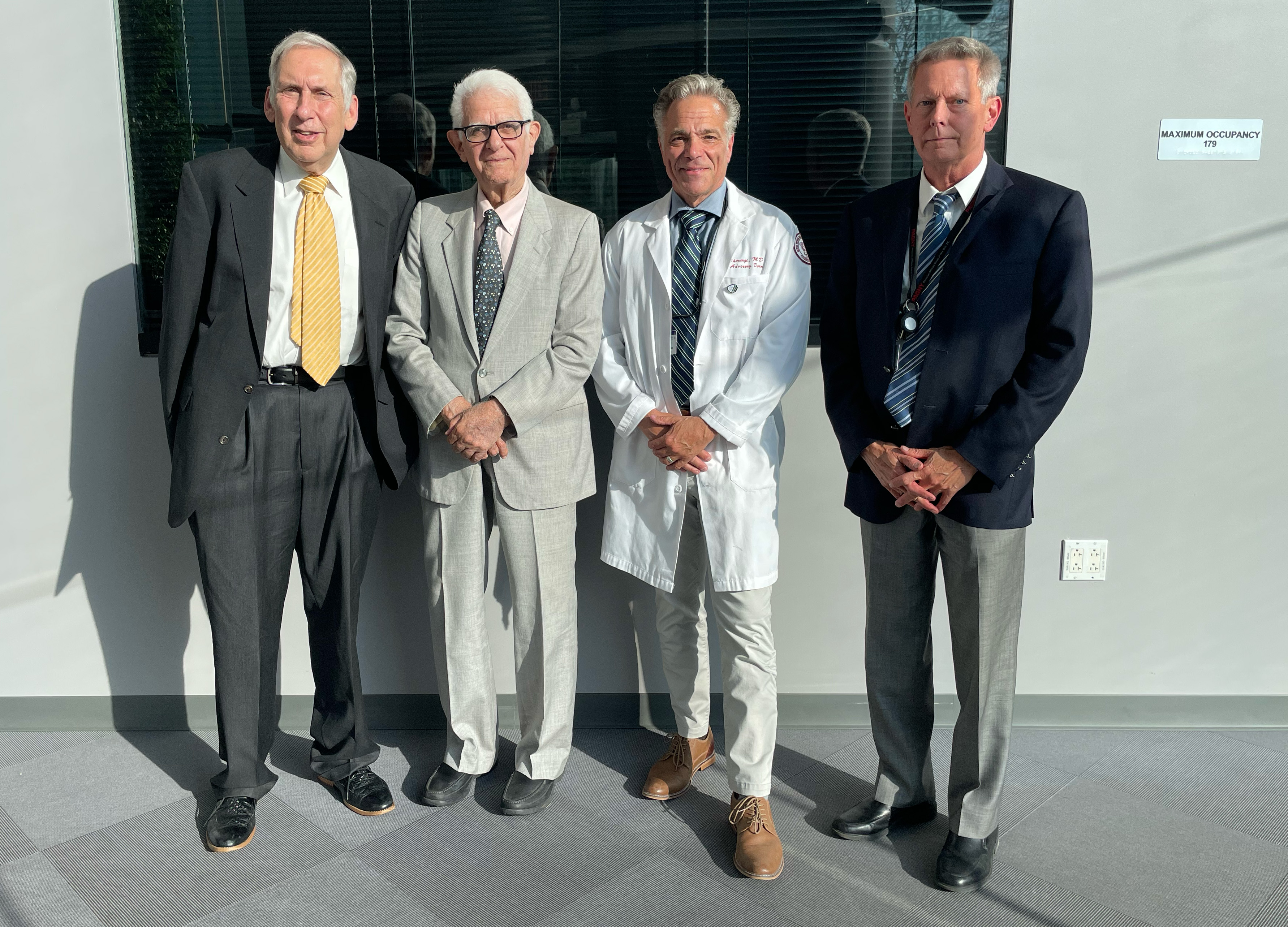 Four older men wearing suits inside a building