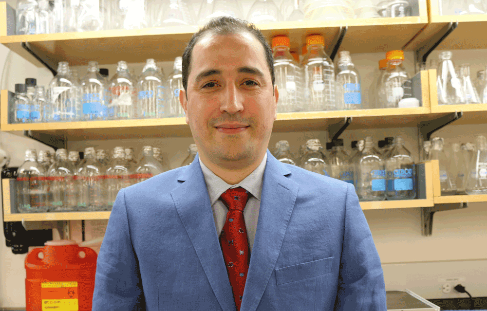 Dr. Abdelfattah El Ouaamari in a suit standing in front of beakers in a lab