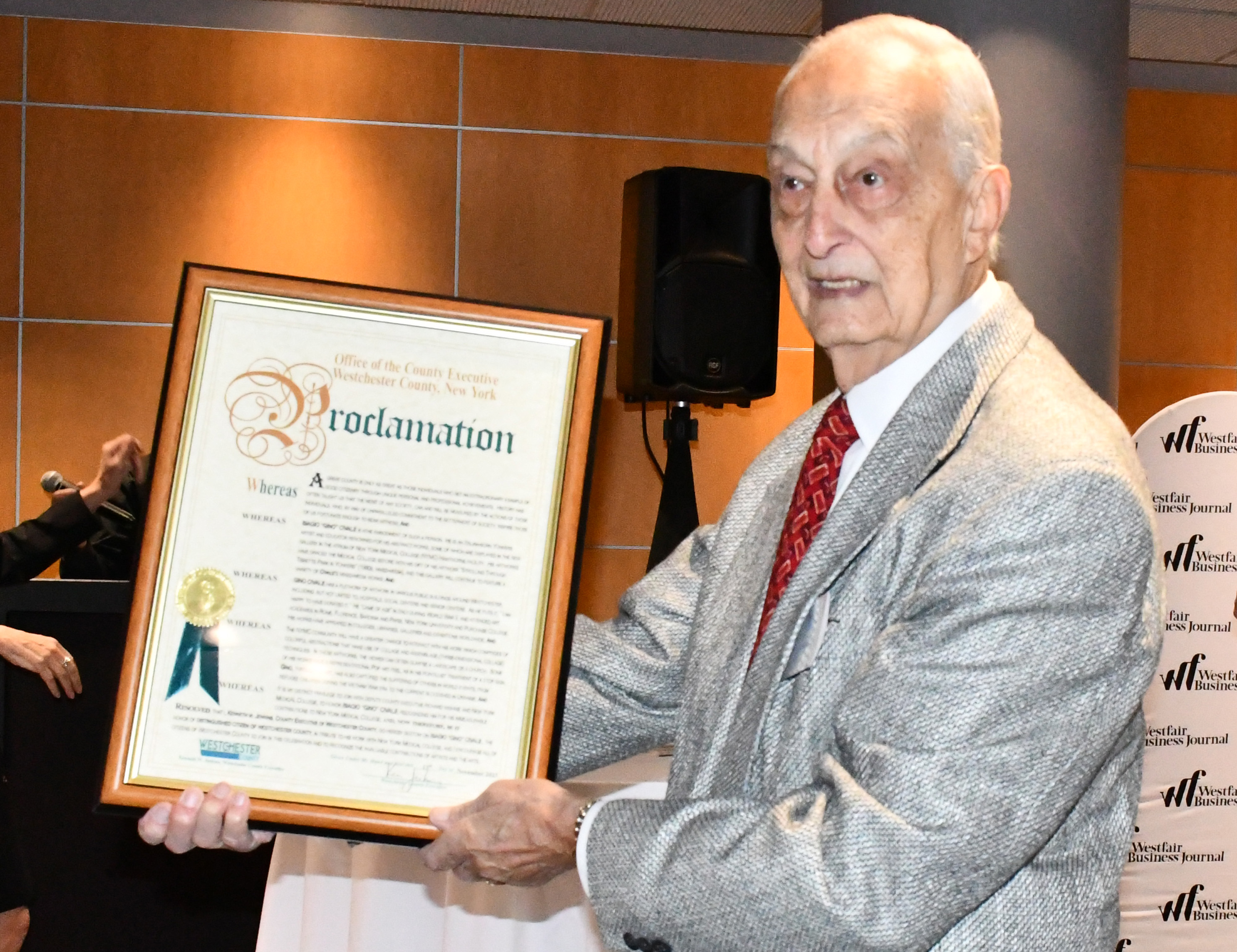 A man wearing a suit holding a framed formal document