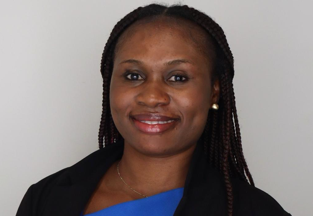 Woman with box braids smiling wearing a dress shirt and blazer.