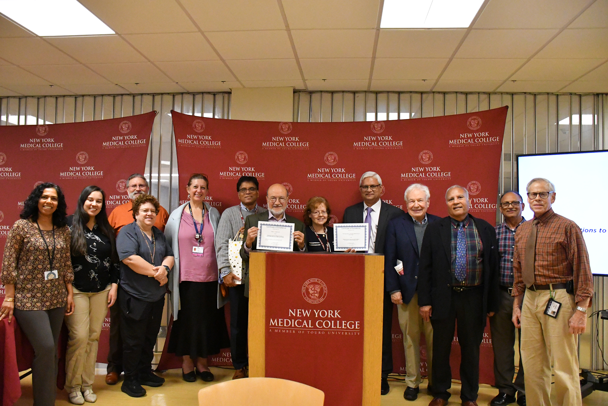 A group of faculty members around a podium with awards smiling