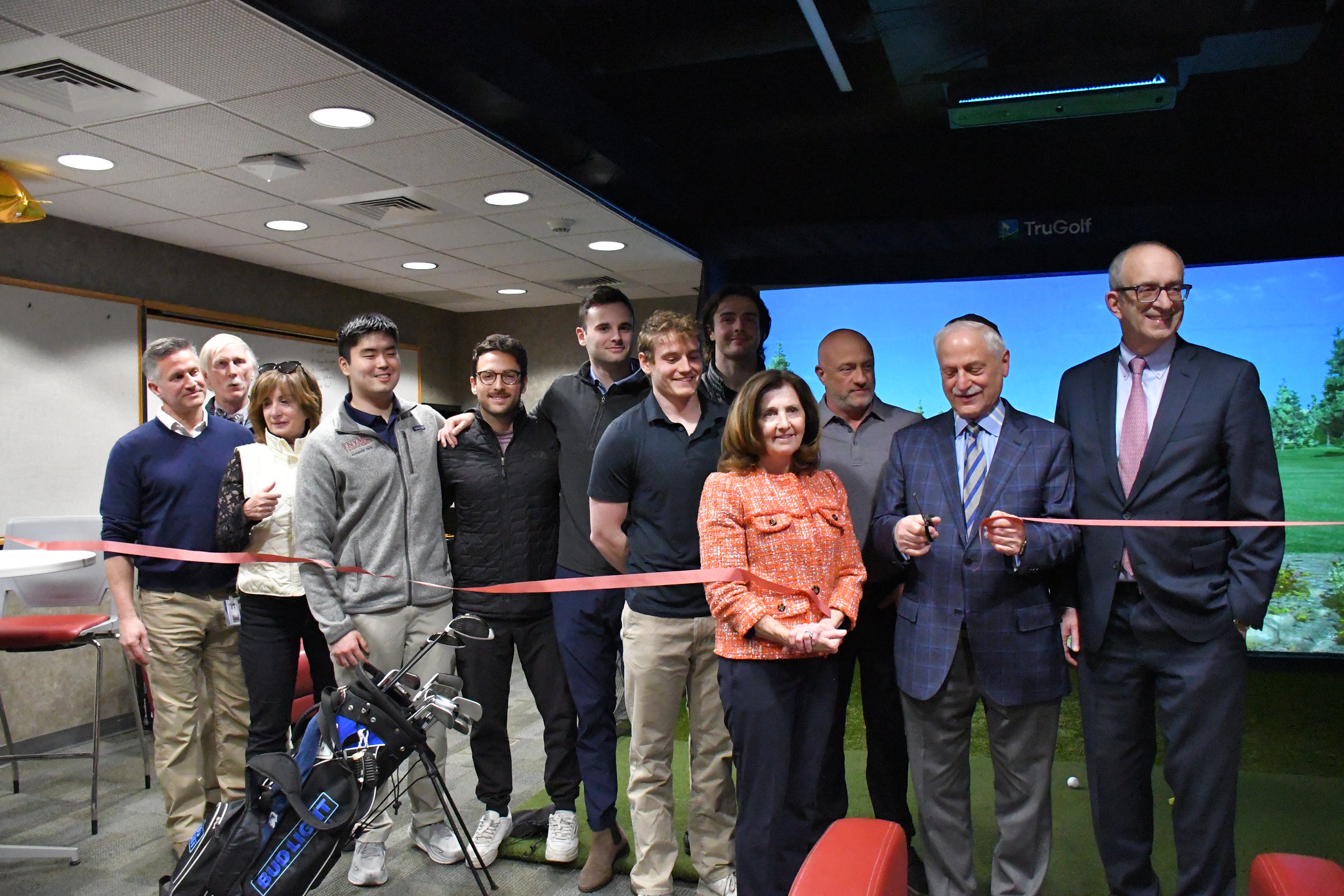 The NYMC community gathering for the golf simulator ribbon cutting event.