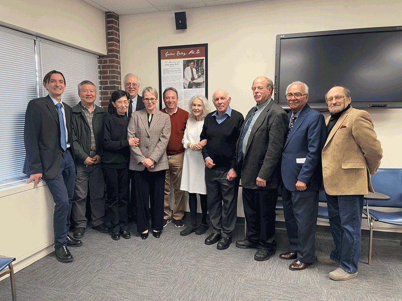 Faculty members from the Department of Physiology standing near the memorial poster of Gabor Kaley, Ph.D., the late faculty member and chair of the Department of Physiology.