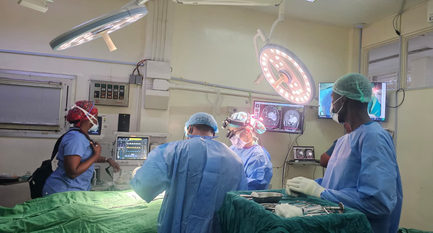 Physicians in scrubs operating in a room with medical equipment.
<br />