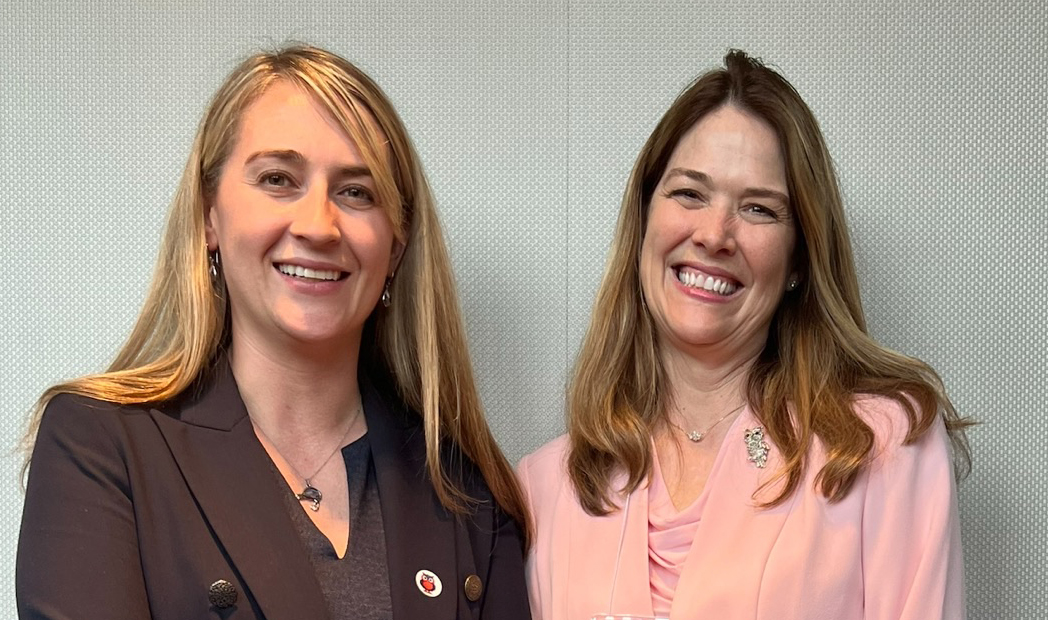 Two women wearing suits smiling