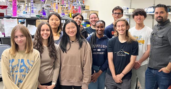 A professor standing with a group of students in a science lab