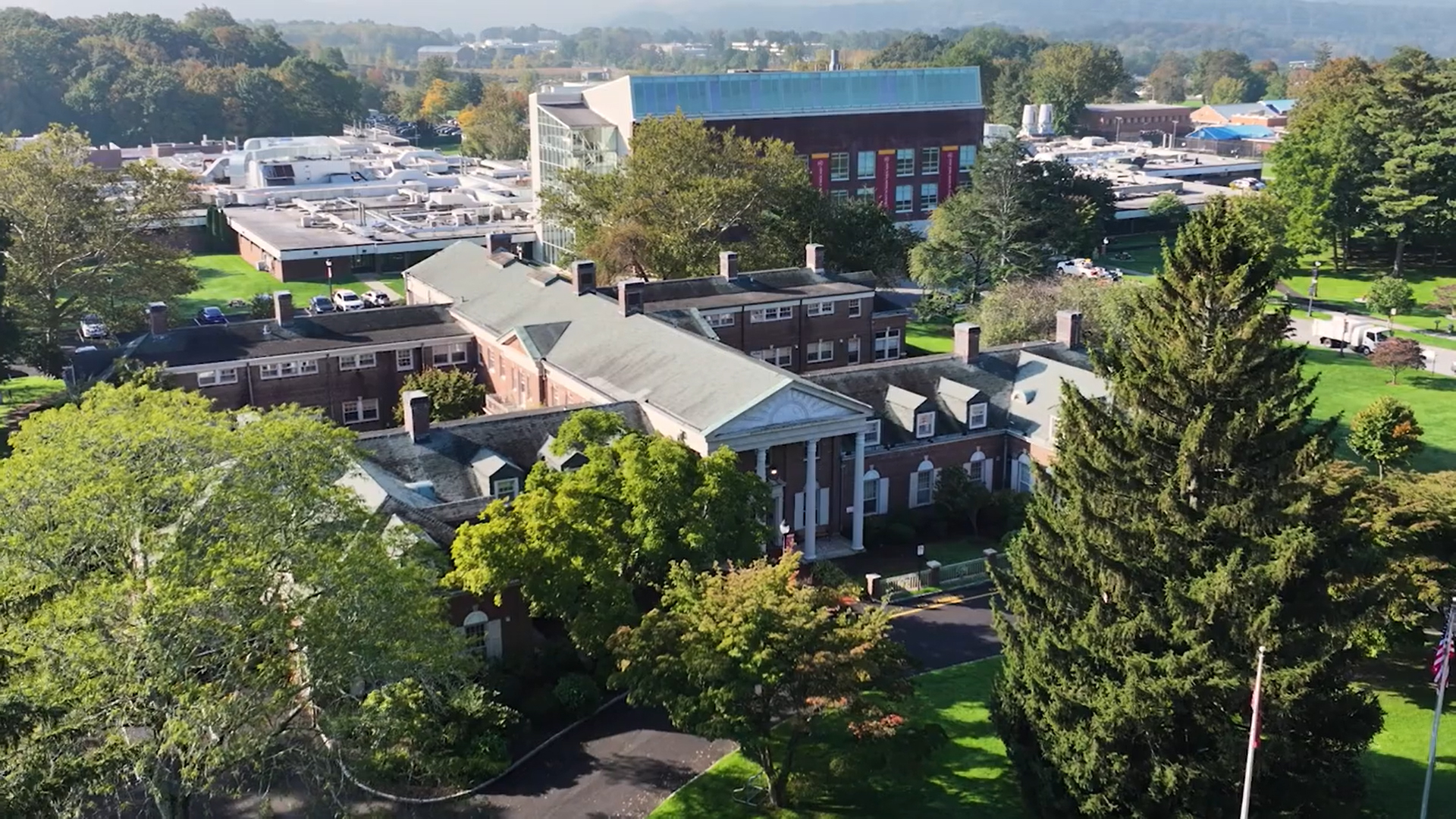 Aerial shot of two buildings surrounded by green trees and grass