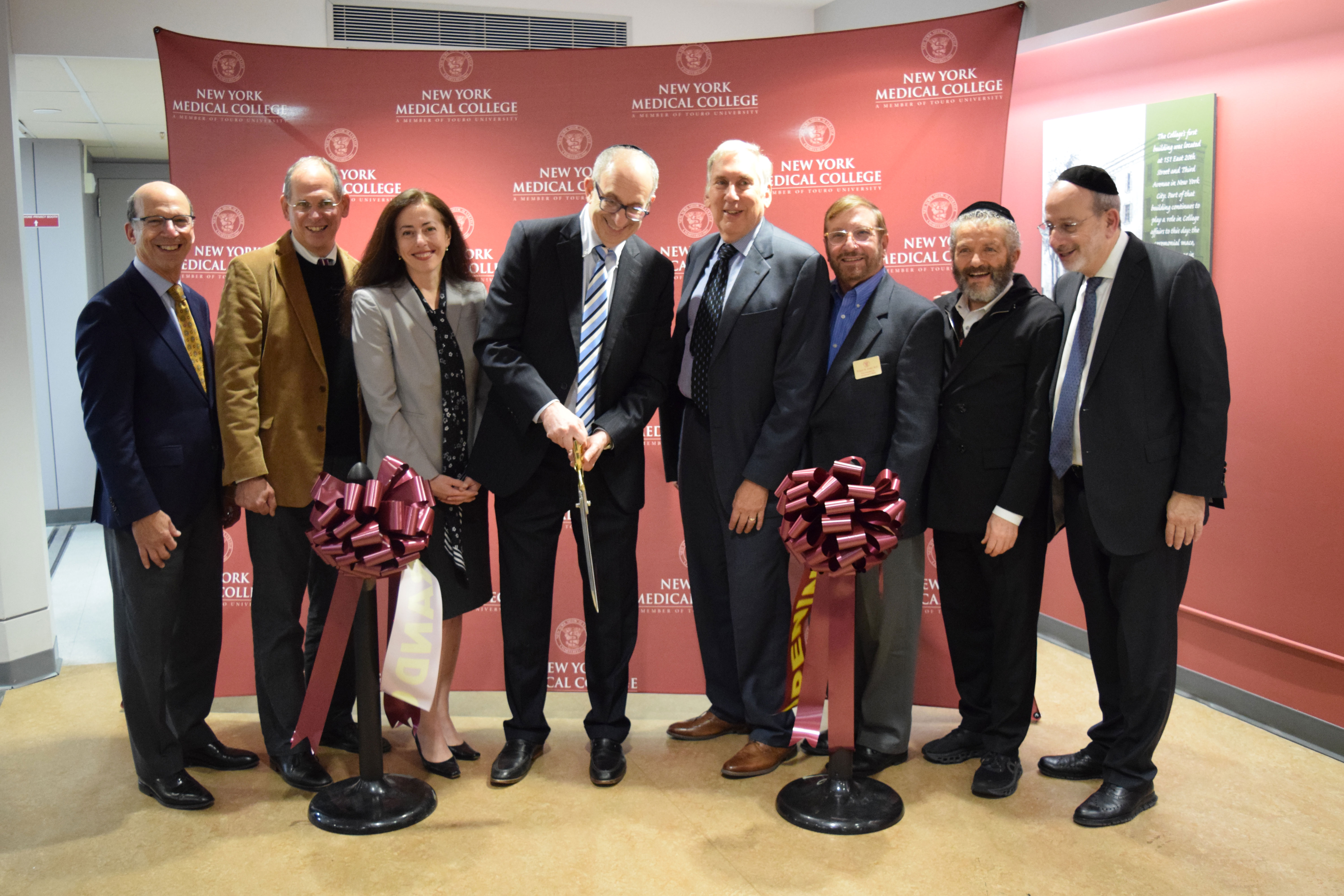 Seven men and women cutting a ribbon for a grand opening