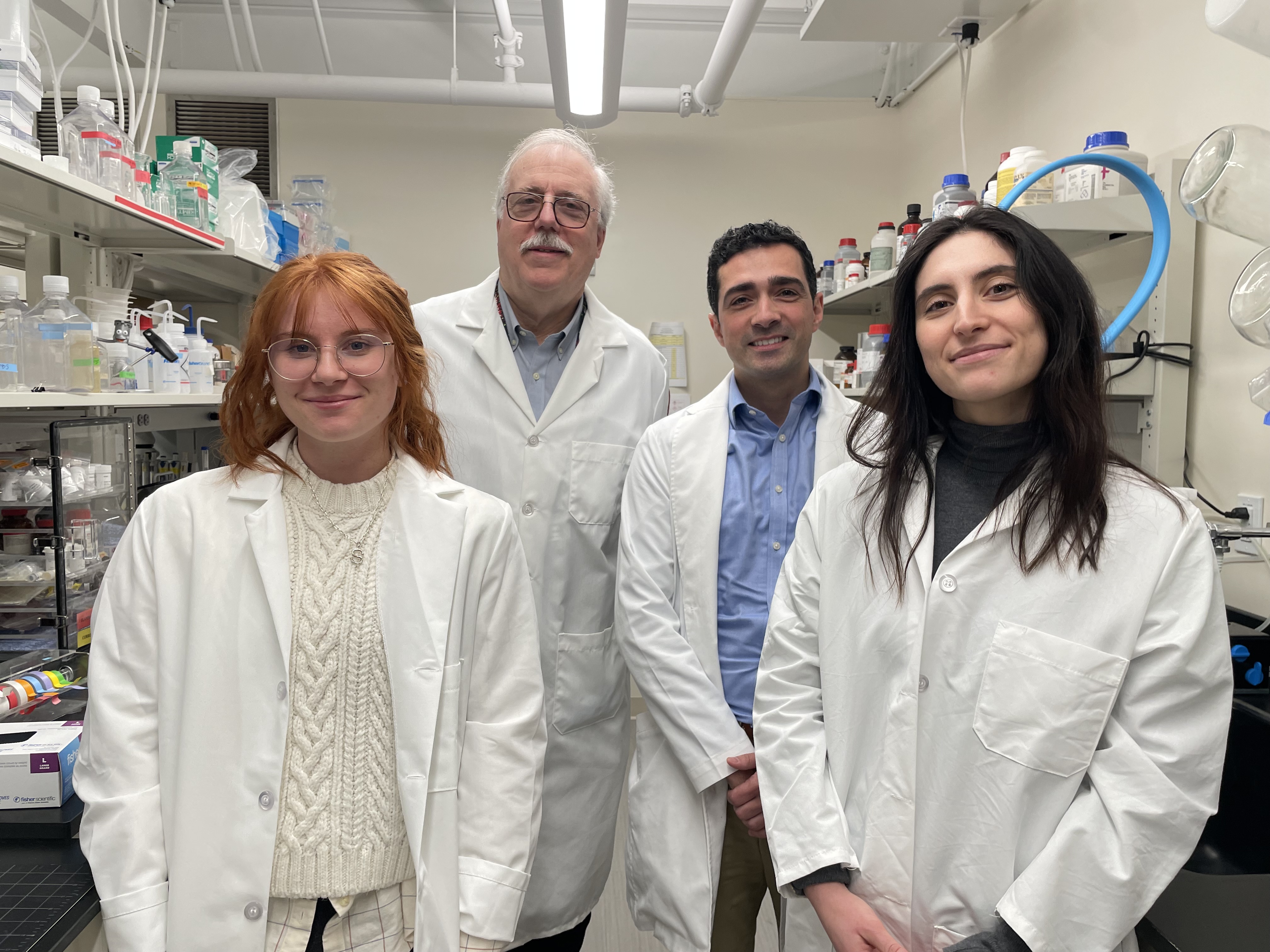 Graduate students and faculty in whit coats in a lab.