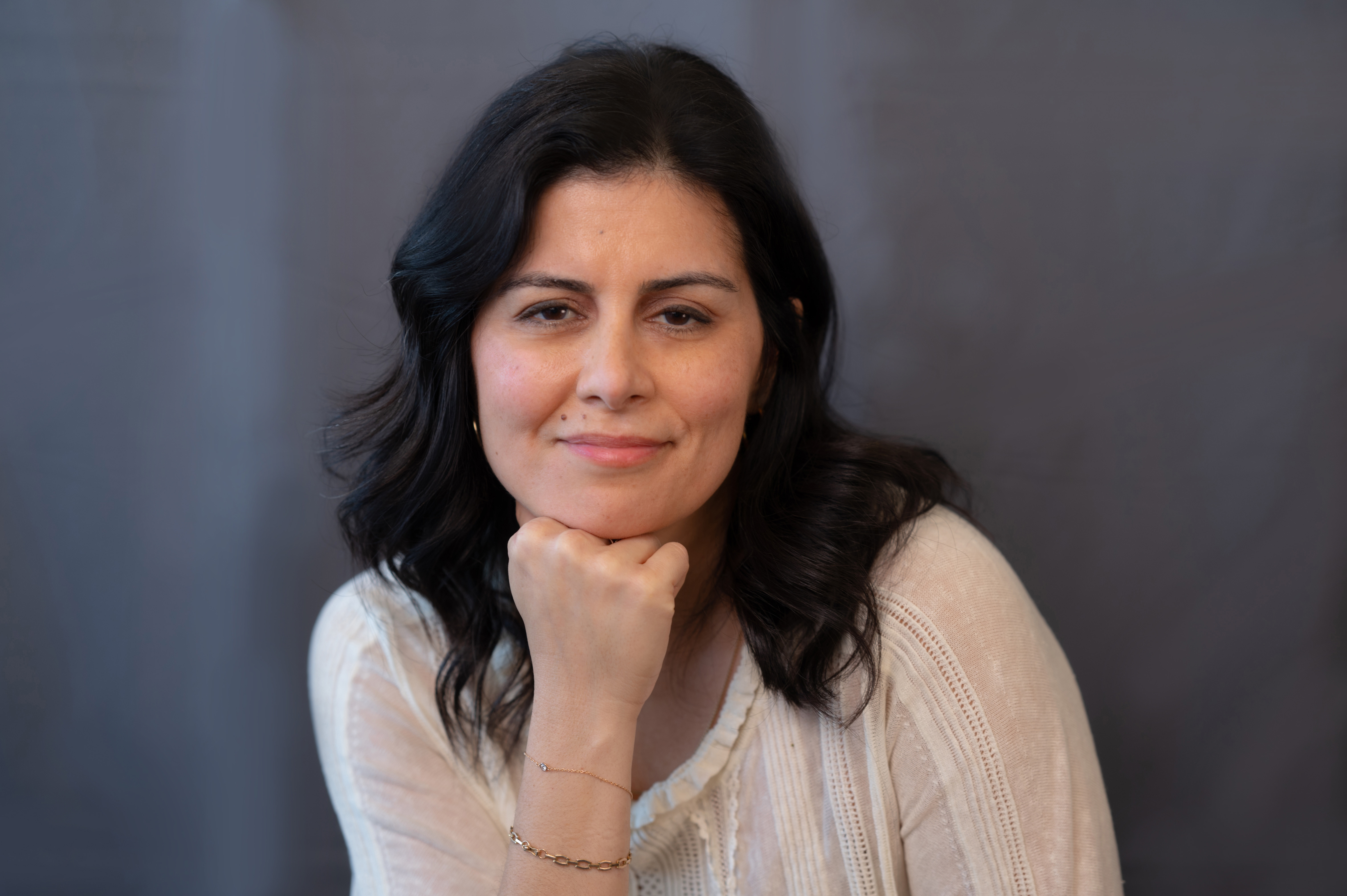 Woman smiling with hand on chin wearing a sweater