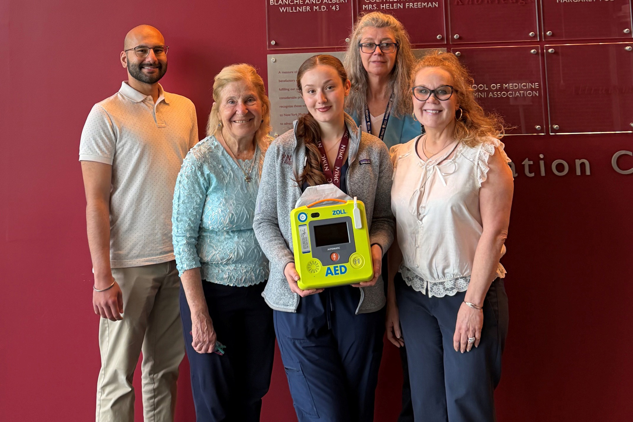 Man and women indoors with holding an AED machine