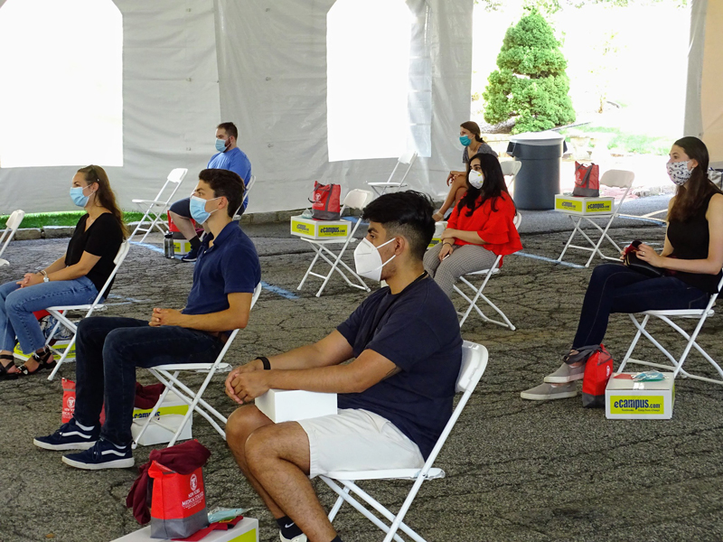 Students sitting on chairs outside during medical school orientation event