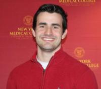 Man smiling in front of New York Medical College backdrop