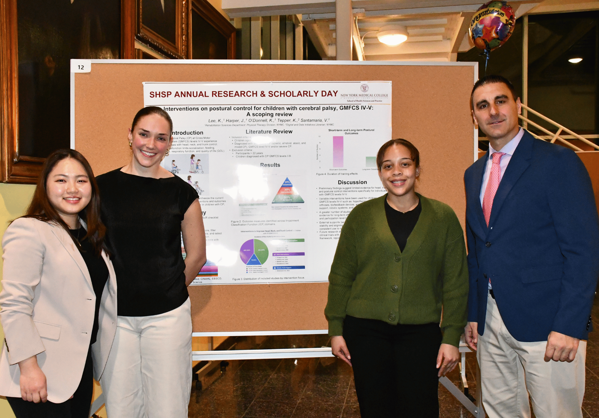 Four people smiling in front of poster presentation