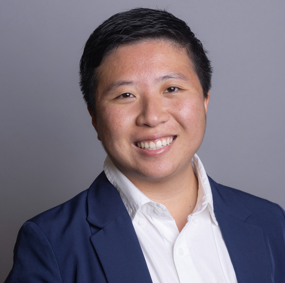 Person smiling wearing navy blazer in front of grey background