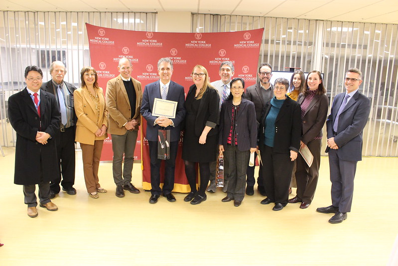 Faculty award recipients stand in front of the NYMC step-and-repeat banner 