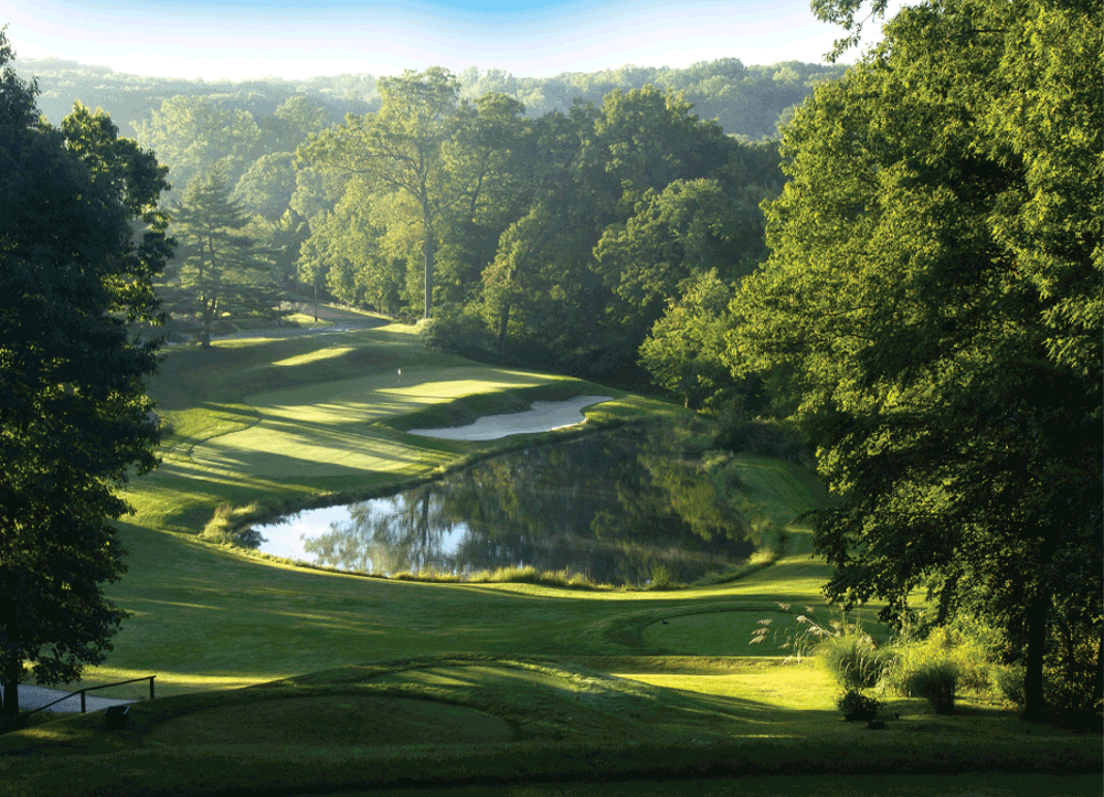 Lush green hilly golf course with lake