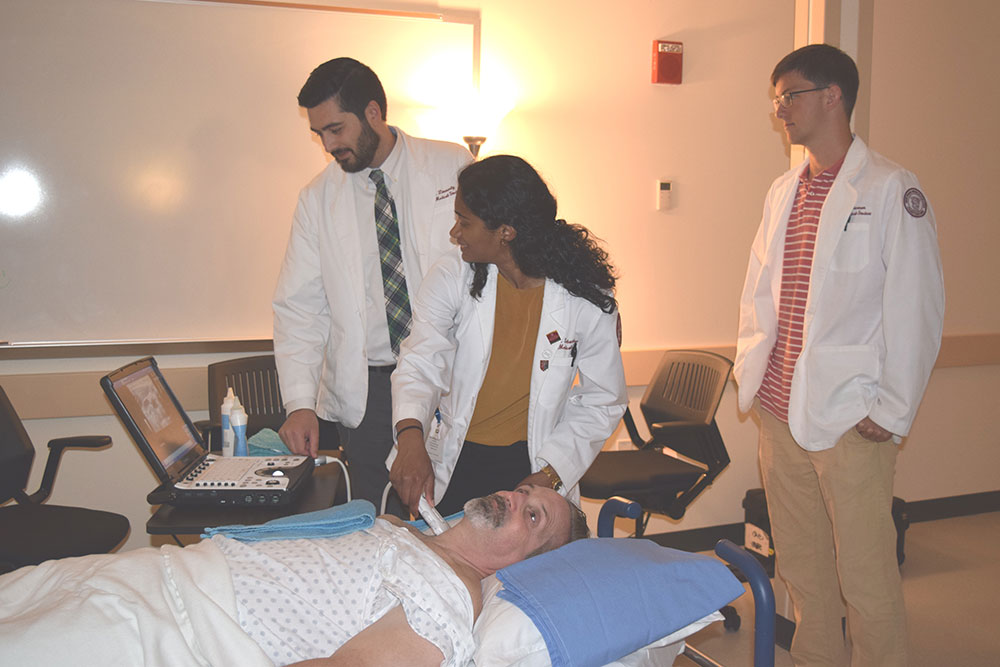 Students examining a patient 
<br />