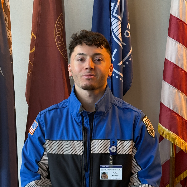 Man in blue and black jacket in front of flags