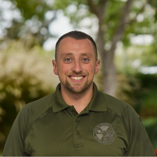 Man in green shirt in front of trees