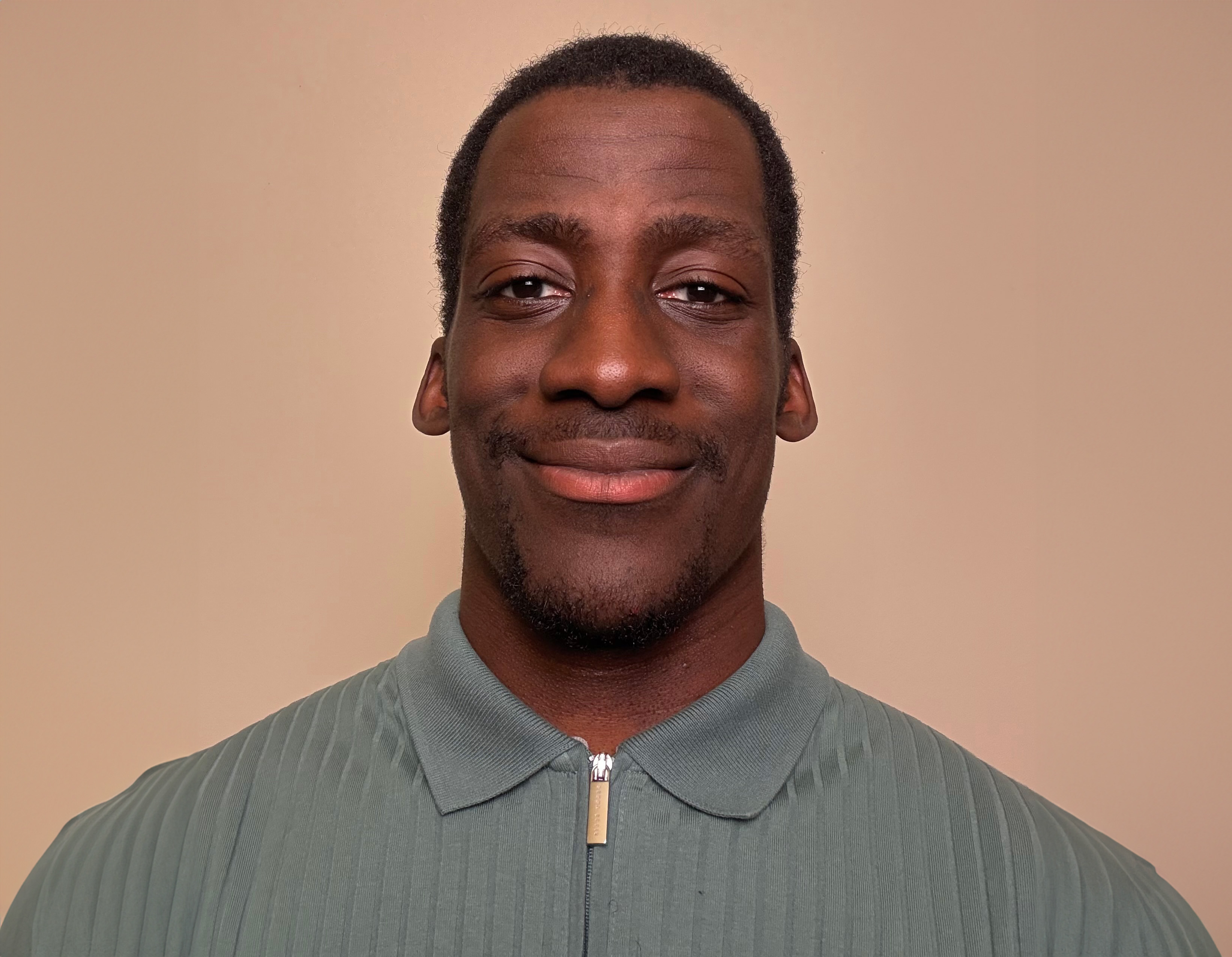 Portrait shot of Black man, lead author of the study, in front of tan background